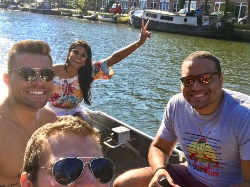 Drie vrouwen en een man in witte kleding op een boot met een Boats4rent-medewerker op de kade