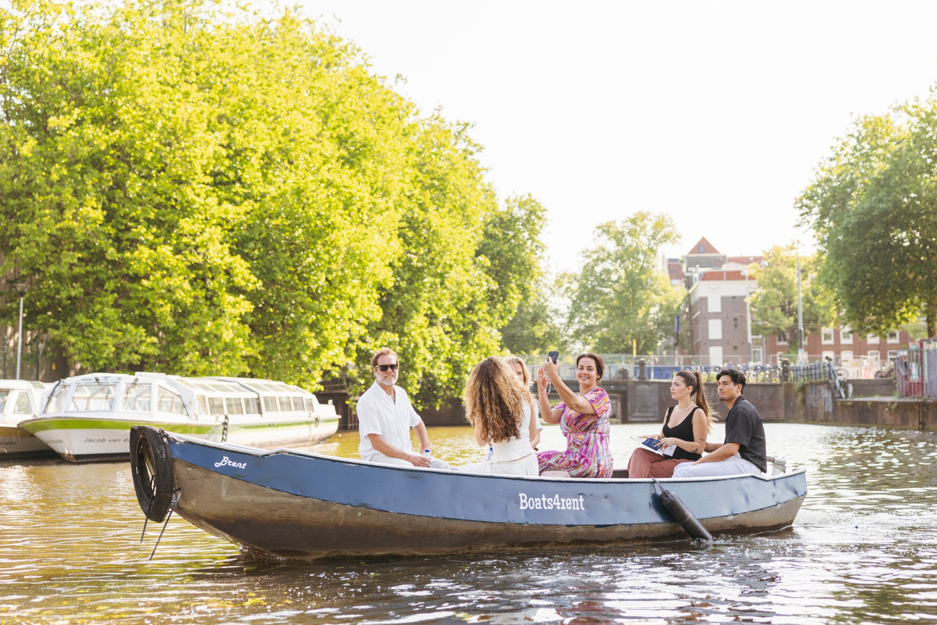 Group cruising in electric boat past Amsterdam windmill