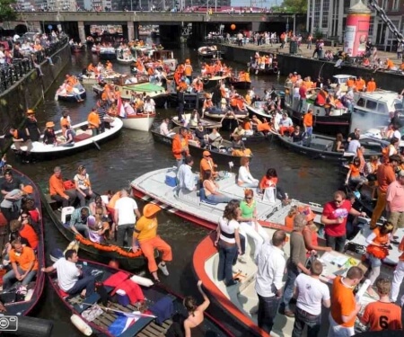 Various boats on the canals of Amsterdam during King's Day.